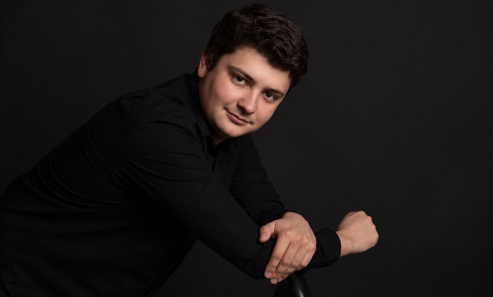 Мужчина в черной рубашке на темном фоне.png